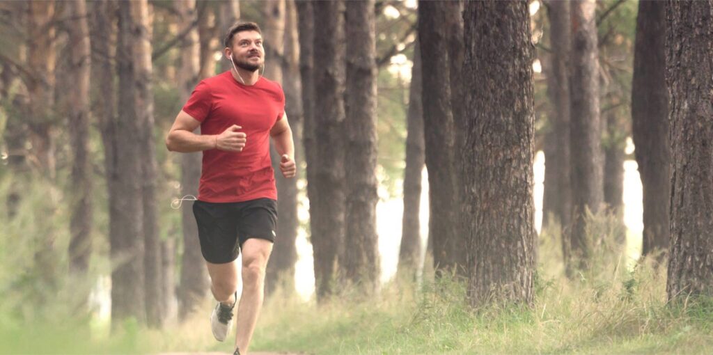 Homme qui court dans un parc boisé